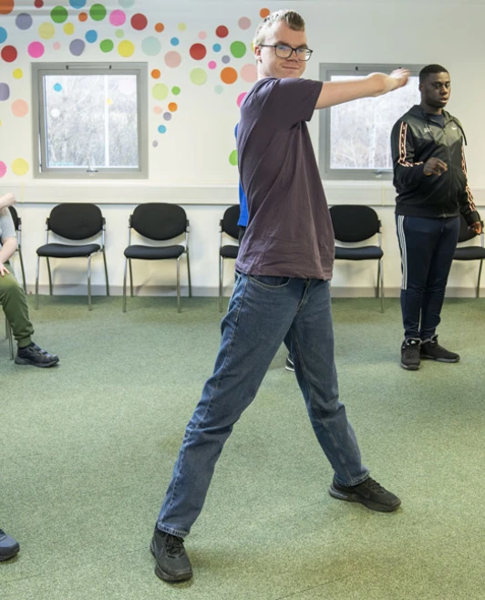 Group of young men stretching and exercising in a colorful room during a physical activity session. Group of young men stretching and exercising in a colorful room during a physical activity session.